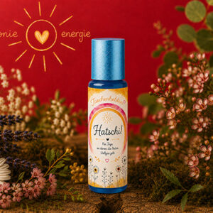 Aroma-Roll-on Hatschi aus der Serie Taschenhelden von Harmonie Energie, umgeben von getrockneten Kraeutern und Blueten