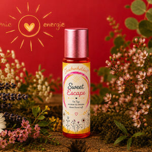 Aroma-Roll-on Sweet Escape aus der Serie Taschenhelden von Harmonie Energie, umgeben von getrockneten Kraeutern und Blueten